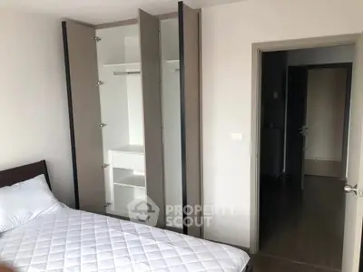 Modern bedroom with open wardrobe and comfortable bed in a stylish apartment.