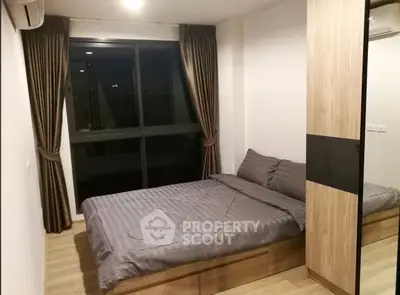 Modern bedroom with large window and stylish wooden wardrobe in a cozy apartment.