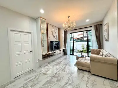 Elegant living room with chandelier and modern decor, featuring a spacious layout and large windows.