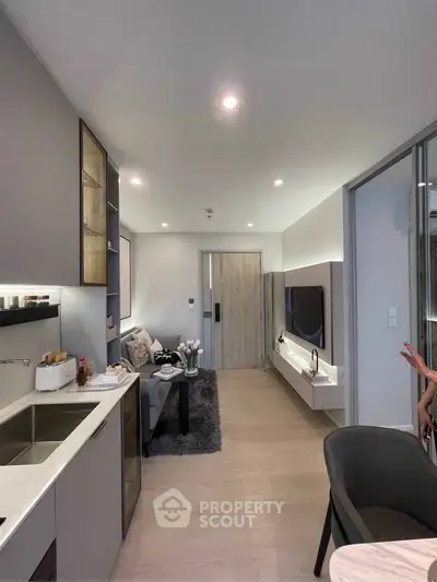 Modern open-layout living room with sleek kitchen and cozy seating area, perfect for urban living.