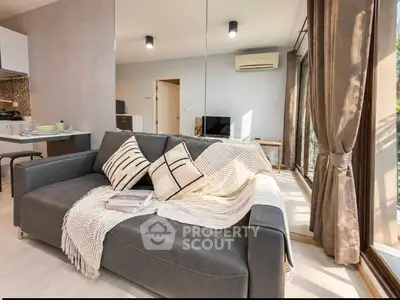 Stylish modern living room with cozy sofa and large windows offering natural light.