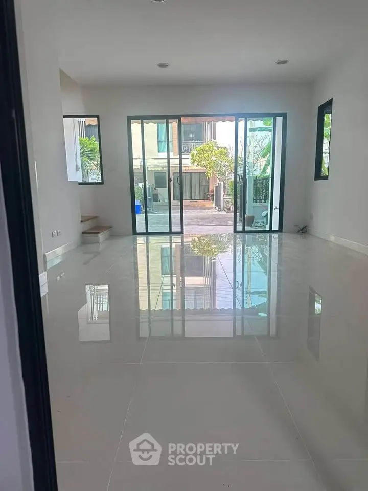 Spacious modern living room with large windows and glossy tile flooring, offering a bright and airy ambiance.