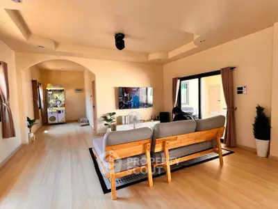 Spacious living room with modern decor and natural light, featuring a cozy seating area and entertainment setup.