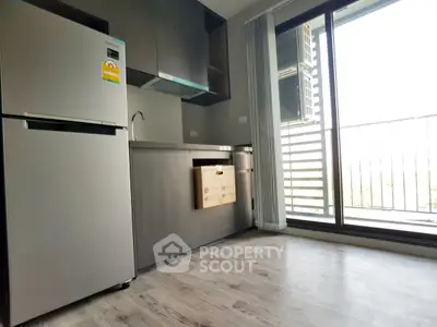 Modern kitchen with stainless steel fridge and balcony view in a stylish apartment.