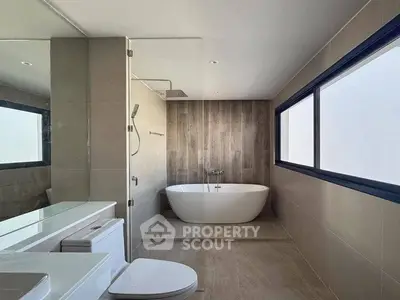 Luxurious modern bathroom with freestanding bathtub and large windows.