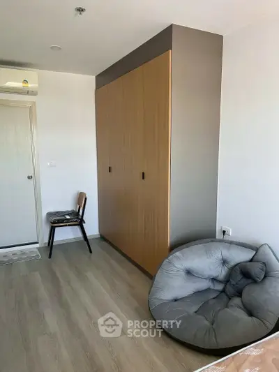 Cozy bedroom with modern wardrobe and plush seating, perfect for relaxation.