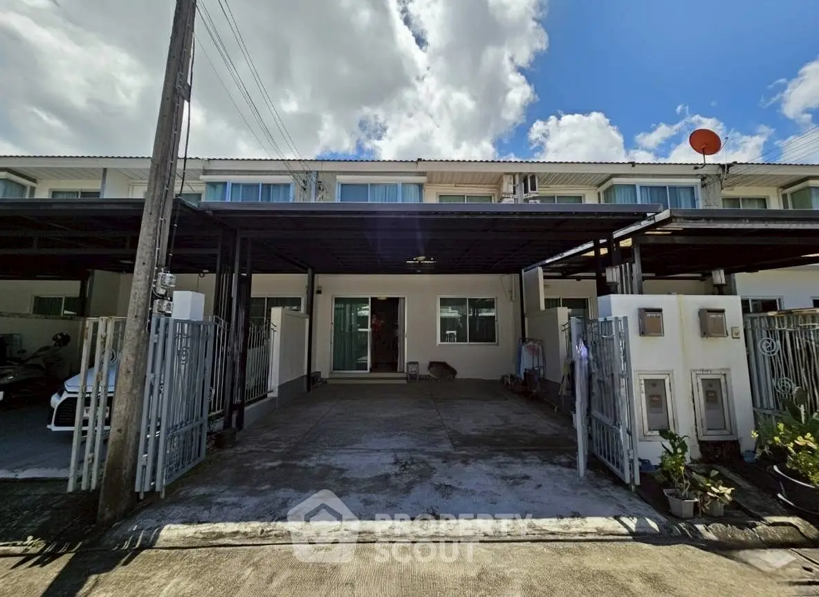 Modern townhouse with covered parking and sleek exterior design under a bright blue sky.