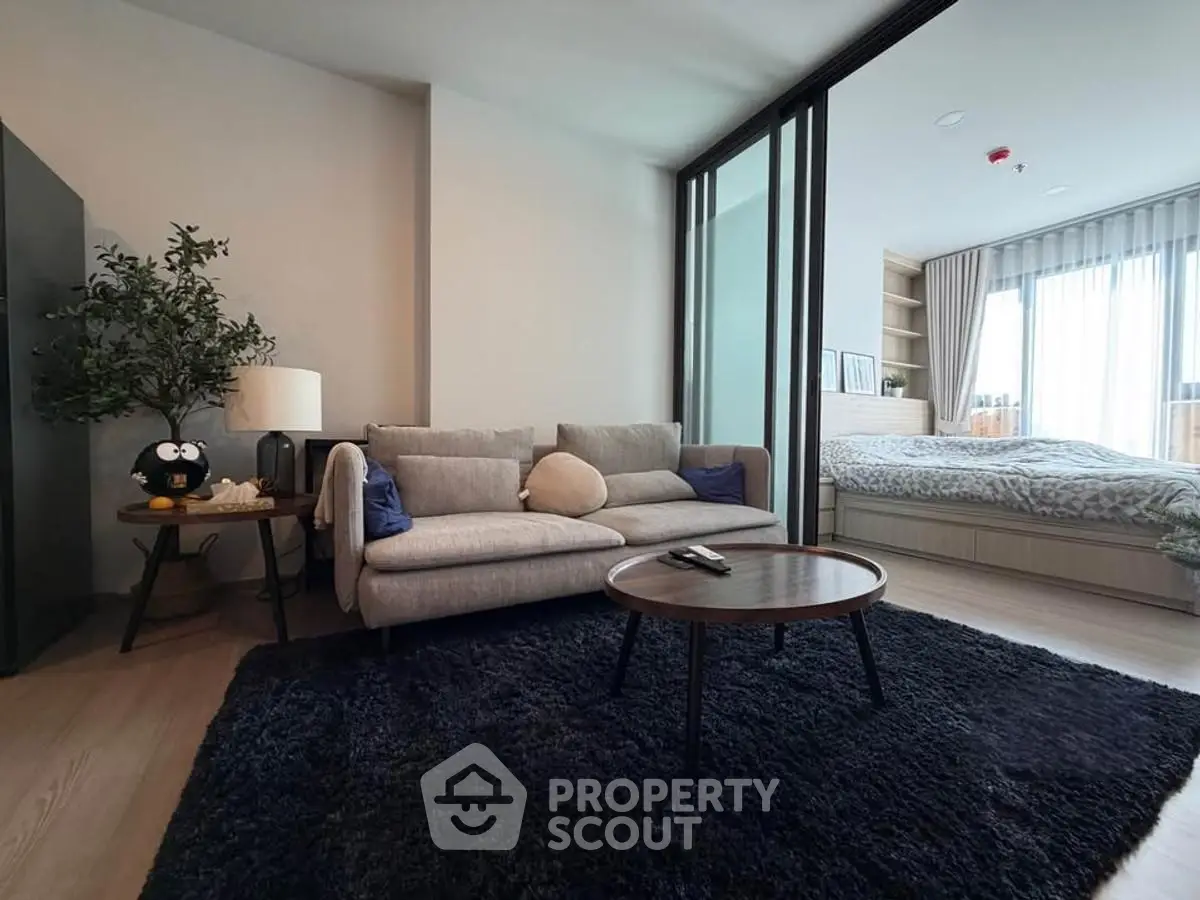 Modern living room with cozy sofa and stylish decor adjacent to a bedroom