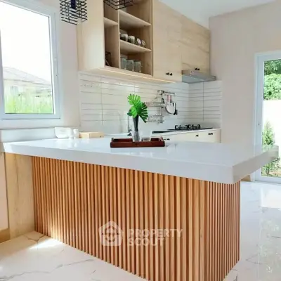 Modern kitchen with sleek island and open shelving, featuring a gas stove and elegant design.