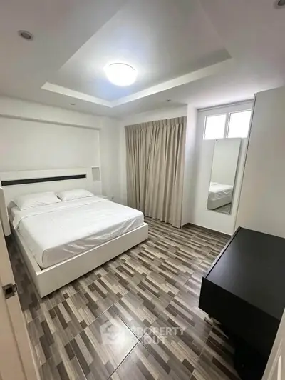 Modern bedroom with stylish flooring and cozy ambiance in a contemporary apartment.