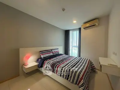 Modern bedroom with stylish decor and natural light, featuring a comfortable bed and air conditioning.