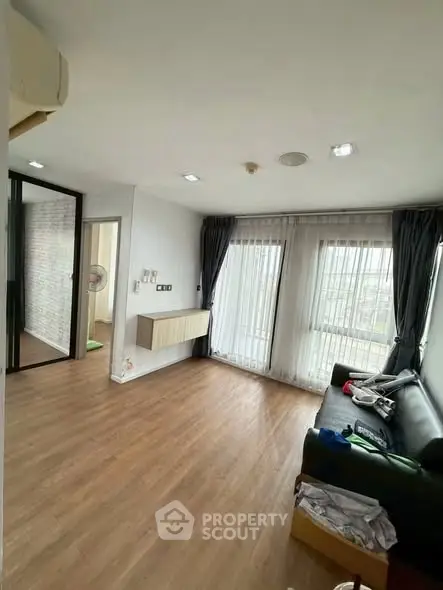 Spacious living room with large windows and modern decor in a stylish apartment.