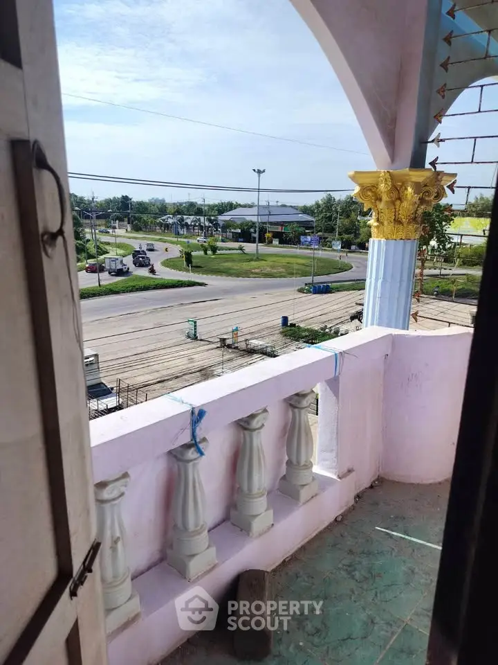 Charming balcony view overlooking a scenic roundabout with lush greenery and clear skies.
