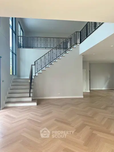 Spacious modern living room with elegant staircase and herringbone wood flooring