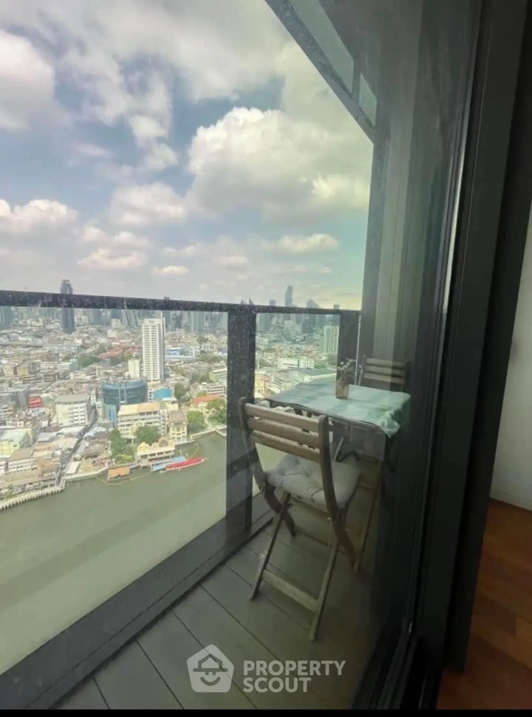 Stunning cityscape view from a high-rise balcony with cozy seating area.