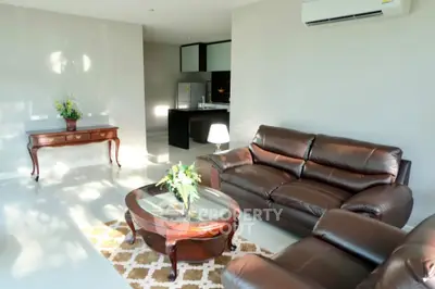 Spacious living room with elegant leather sofas and stylish wooden furniture, perfect for relaxation.