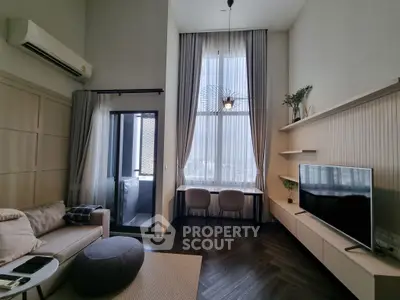 Modern living room with high ceilings, elegant decor, and large windows offering natural light.