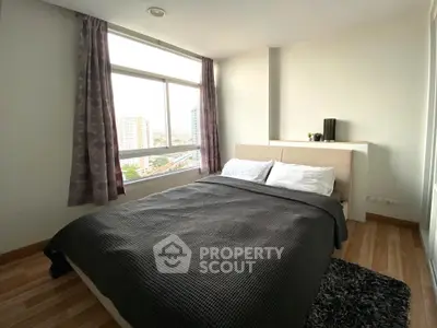 Spacious bedroom with large window offering stunning city views, modern decor, and cozy ambiance.