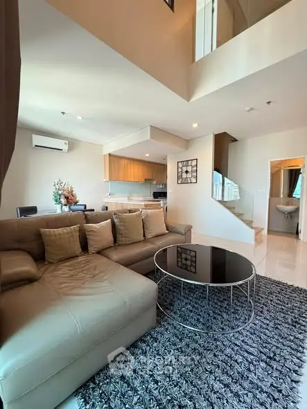 Spacious modern living room with open kitchen and stylish decor in a duplex apartment.