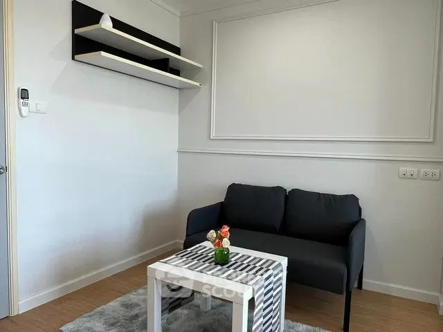 Modern minimalist living room with sleek black sofa and stylish shelves.