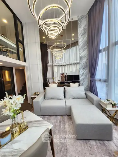 Luxurious modern living room with high ceilings and elegant lighting fixtures.