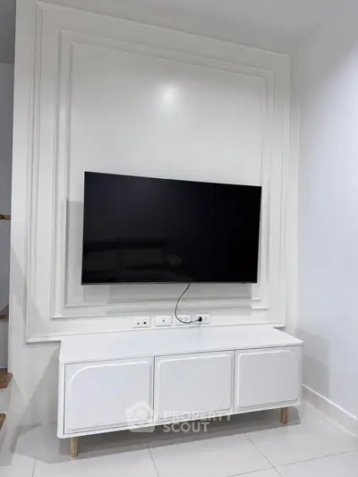 Modern living room with sleek TV setup and elegant white cabinetry
