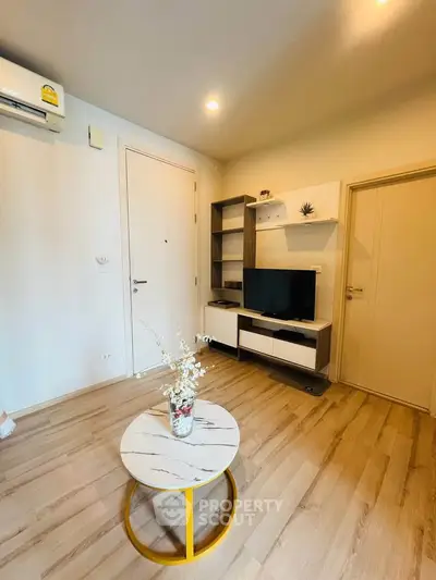 Modern living room with stylish furniture and wooden flooring, featuring a TV unit and decorative accents.