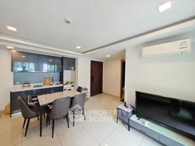 Modern living room with sleek kitchen and dining area, featuring contemporary furniture and bright lighting.