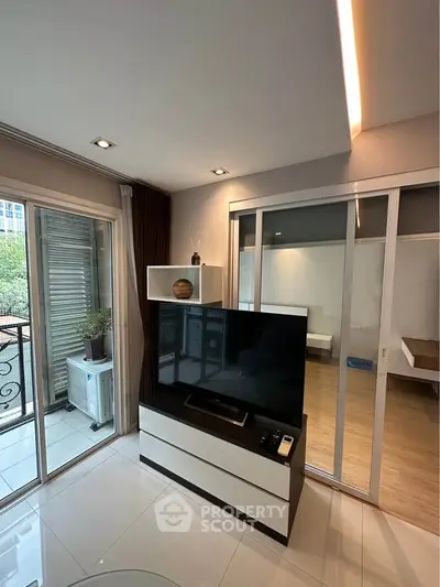 Modern living room with sleek TV stand and sliding glass doors leading to a balcony.