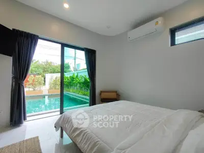 Modern bedroom with pool view, featuring large windows and air conditioning, offering a serene and luxurious ambiance.
