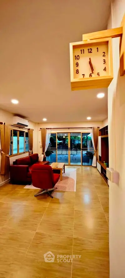 Spacious living room with modern decor and large windows opening to a garden view.