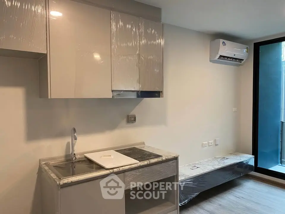 Modern kitchen with sleek cabinetry and air conditioning in a contemporary apartment.