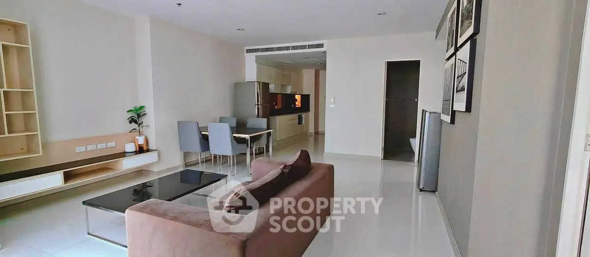 Spacious modern living room with sleek furniture and dining area in open layout apartment.
