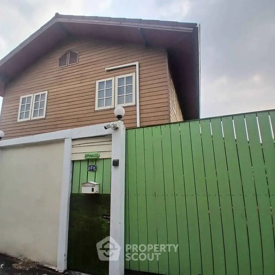 Charming wooden house with green fence and classic architecture, perfect for cozy living.