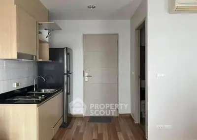 Modern compact kitchen with sleek appliances and wooden cabinetry in a cozy apartment.