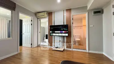 Modern living room with wooden flooring, TV, and access to bathroom and bedroom.