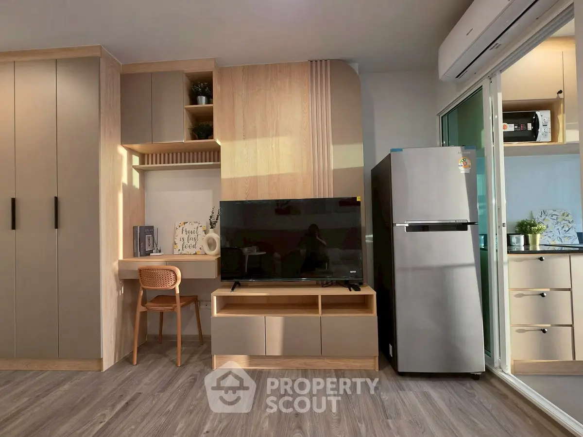 Modern living room with sleek furniture, built-in storage, and stainless steel fridge, perfect for urban living.