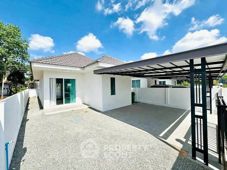Charming single-story home with spacious driveway and modern carport under a clear blue sky.