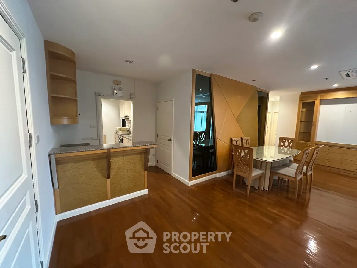 Spacious open-plan living and dining area with elegant wooden flooring and modern kitchen design.