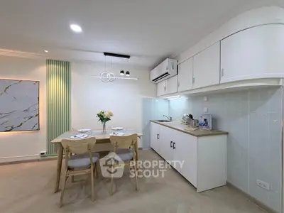 Modern kitchen with dining area, featuring sleek cabinetry and elegant lighting.