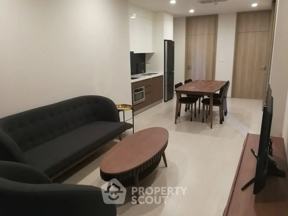 Modern living room with sleek furniture and open kitchen layout in a stylish apartment.
