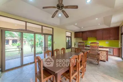 Spacious kitchen with wooden dining set and garden view, featuring open layout and ceiling fan.