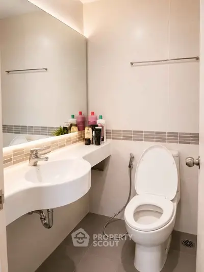 Modern bathroom with sleek fixtures and contemporary design, featuring a spacious mirror and elegant tiling.