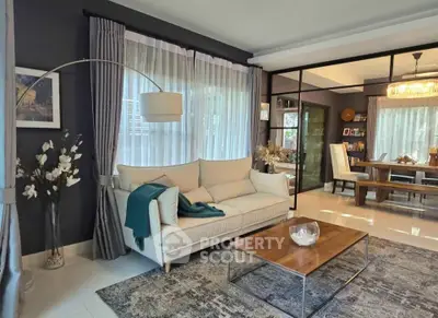 Elegant living room with modern decor and open dining area, featuring stylish furniture and large windows.