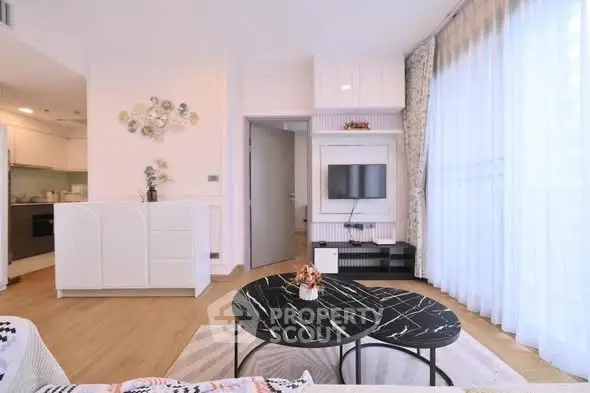 Modern living room with stylish decor and natural light, featuring a sleek TV setup and elegant furniture.