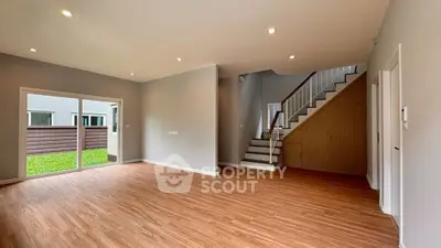 Spacious modern living room with wooden flooring and staircase in a bright home.