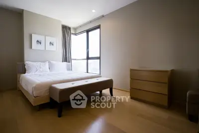 Spacious modern bedroom with large window and elegant wooden furniture.