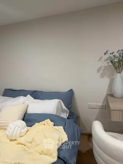 Cozy bedroom with modern decor, featuring a plush bed and elegant vase on a wooden shelf.