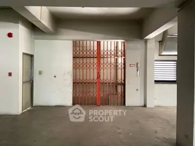 Spacious industrial-style building entrance with metal gate and concrete flooring.