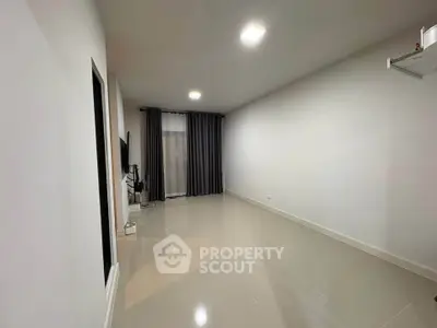 Spacious minimalist living room with sleek tile flooring and modern lighting, perfect for contemporary living.